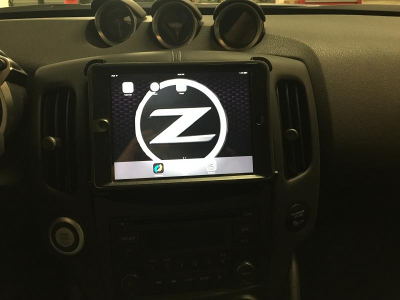 iPad mini with Otter box Defender case mounted over dash center cubby.
