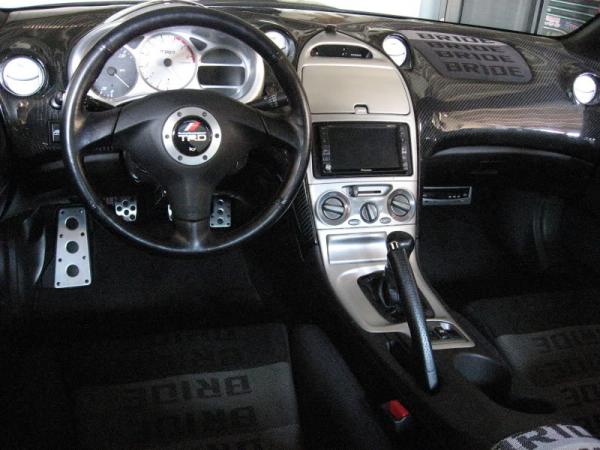 TRD Supra Steering Wheel Red Stitched, Custom CF Dash, Color Coded Vents, Center Console, Custom TRD Center Tach/Speed Gauge Blue L.E.D., Full Suede JDM Bride Interior, 2003 Black Panel Interior Swap, JDM Toyota Window Visors, JDM Celica Alluminum Door Sill Plates, CF Armrest, TRD Short Shifter